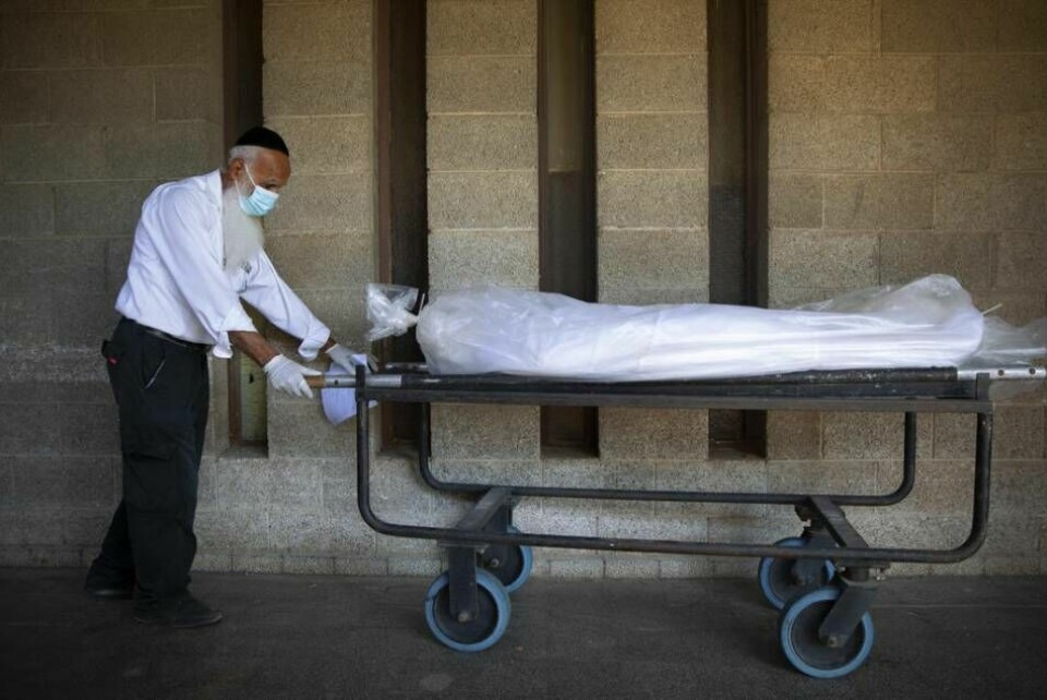 En anställd vid Israel begravningsmyndighet för en kropp till ett särskilt bårhus avsett för personer som avlidit av covid-19. Foto: Oded Balilty/AP/TT