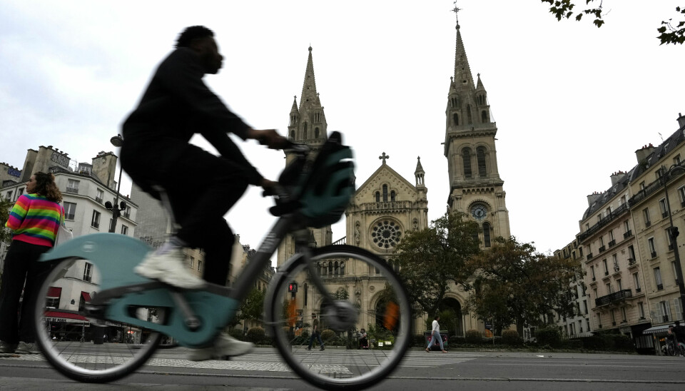 En person cyklar förbi en katolsk kyrka i Paris.