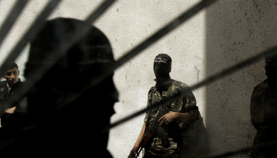 En maskerad man från Al-Aqsamartyrernas brigader står utanför en byggnad i Gaza.