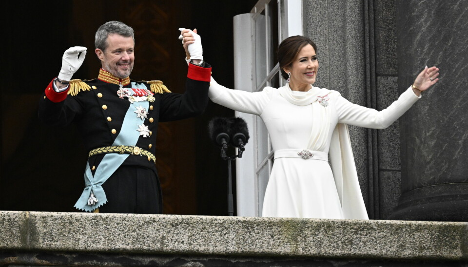 Kung Frederik X och drottning Mary vinkar från balkongen.