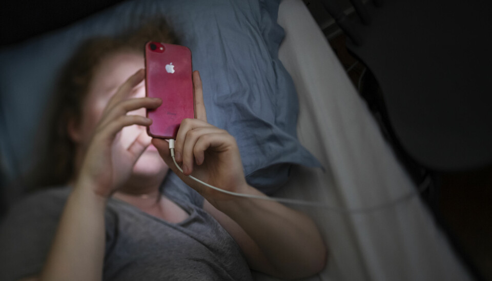 Kvinna i sängen med en mobil