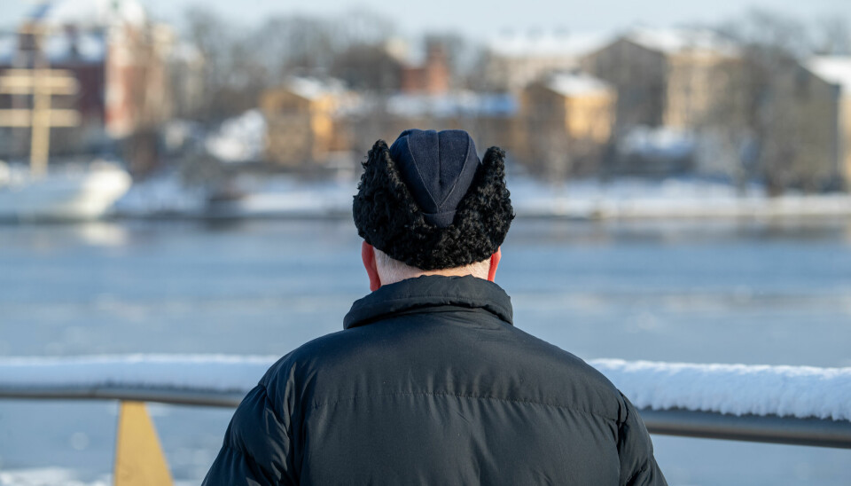 En ensam man med mössa och vinterjacka på promenad i Stockholm.