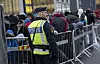 En polis övervakar kön av ankommande flyktingar i snålblåsten vid Hyllie station i Malmö hösten 2015.