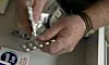 En man plockar upp medicin ur olika förpackningar