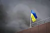 In this photo released by the Dnipro Regional Administration, Ukrainian flag waves as smoke rises after Russia's missile attack in Dnipro, Ukraine, Wednesday, July 3, 2024. (Dnipro Regional Administration via AP) XSG106