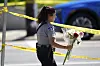 A police officer carries flowers outside the Annunciation Church's school after shooting, Wednesday, Aug. 27, 2025, in Minneapolis. (AP Photo/Abbie Parr) XKS232