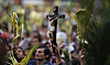 Faithful hold palm fronds and a crucifix during a Palm Sunday Mass at the Baby Jesus Church in Bogota, Colombia, Sunday March 24, 2013. According to the New Testament, Palm Sunday marks the day Jesus rode into Jerusalem, greeted by cheering crowds bearing palm fronds. For Christians, Palm Sunday marks the start of Holy Week. The week continues with commemorations of Jesus' crucifixion on Good Friday before celebrating his resurrection on Easter the following Sunday. (AP Photo/Fernando Vergara)