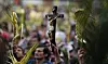 Faithful hold palm fronds and a crucifix during a Palm Sunday Mass at the Baby Jesus Church in Bogota, Colombia, Sunday March 24, 2013. According to the New Testament, Palm Sunday marks the day Jesus rode into Jerusalem, greeted by cheering crowds bearing palm fronds. For Christians, Palm Sunday marks the start of Holy Week. The week continues with commemorations of Jesus' crucifixion on Good Friday before celebrating his resurrection on Easter the following Sunday. (AP Photo/Fernando Vergara)