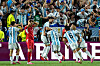 Argentina-spelare i blå- och vitrandiga tröjor firar ett mål framför jublande publik.
