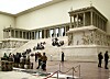 Besökare sitter på trappan till det monumentala Pergamonaltaret inomhus på ett museum i Berlin.
