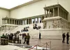 Besökare sitter på trappan till det monumentala Pergamonaltaret inomhus på ett museum i Berlin.