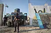 Två maskerade kurdiska säkerhetssoldater med vapen vaktar framför ett militärfordon vid en mur i Kobane.