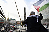 En man viftar med en palestinsk flagga från en höjd ovanför en demonstration på Sergels torg i Stockholm.