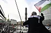 En man viftar med en palestinsk flagga från en höjd ovanför en demonstration på Sergels torg i Stockholm.