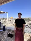 En kvinna står på en takterrass i Jerusalem med Klippdomen och gamla stan i bakgrunden under en blå himmel.