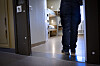 Kriminalvårdare sedd bakifrån i dörröppningen till en fängelsecell med våningssäng på anstalten Kumla.