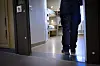 Kriminalvårdare sedd bakifrån i dörröppningen till en fängelsecell med våningssäng på anstalten Kumla.