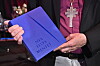 Martin Modéus händer håller en blå bok med titeln Nya testamentet bredvid ett stort silverkors.