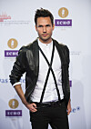 Sångaren Jonas Myrin i svart skinnjacka och vit skjorta poserar framför en logovägg på Echo-galan i Berlin.