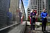 Mette Frederiksen och Jens-Frederik Nielsen talar vid glaspulpeter på ett tak i New York med skyskrapor i bakgrunden.