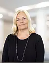 Ljushårig kvinna i svart tröja och halsband mot en suddig ljus bakgrund.