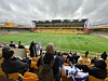 Åskådare med israeliska flaggor på en fotbollsarena med gula stolar under en mulen himmel.