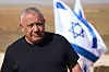 Gadi Eisenkot i svart t-shirt framför en israelisk flagga i ett ökenlandskap nära Gaza.