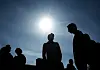 Silhuetter av ungdomar i Stockholm mot en starkt lysande aprilsol på en klarblå himmel.