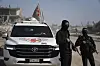Två beväpnade maskerade män står bredvid en vit Toyota tillhörande Internationella Rödakorskommittén.