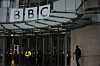 En person går utanför entrén till BBC:s huvudkontor i London under den stora logotypen.