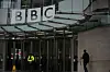 En person går utanför entrén till BBC:s huvudkontor i London under den stora logotypen.